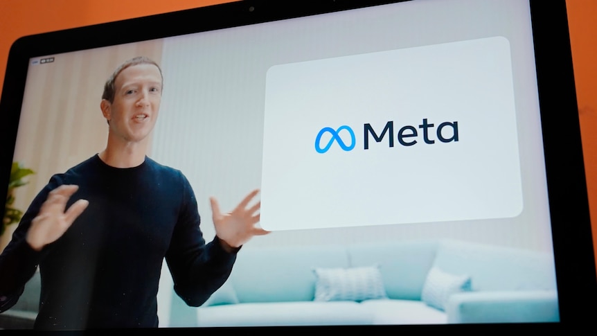 A screen shows a man in a black long sleeve top using his hands to explain a new concept, called Meta. 