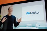 A screen shows a man in a black long sleeve top using his hands to explain a new concept, called Meta. 
