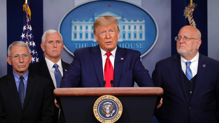 Donald Trump speaks at a press conference and is flanked by Anthony Fauci, Mike Pence and Robert Redfield.