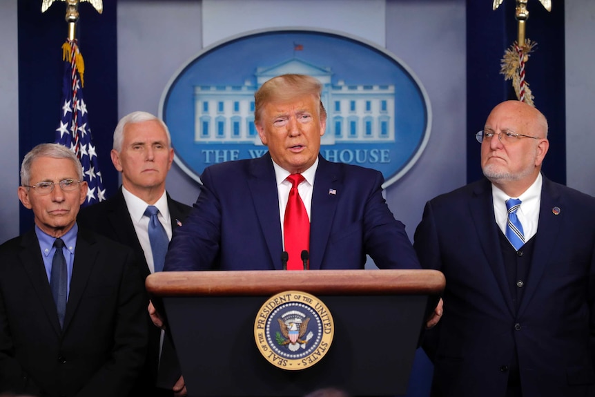 Donald Trump speaks at a press conference and is flanked by Anthony Fauci, Mike Pence and Robert Redfield.