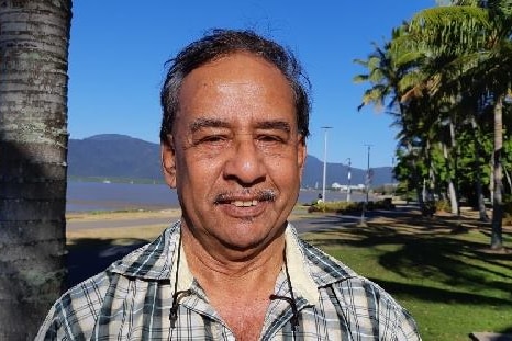 A smiling man looks at the camera with a rural landscape in the background