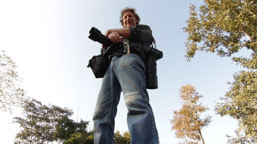 a low angle photo of a man holding many cameras