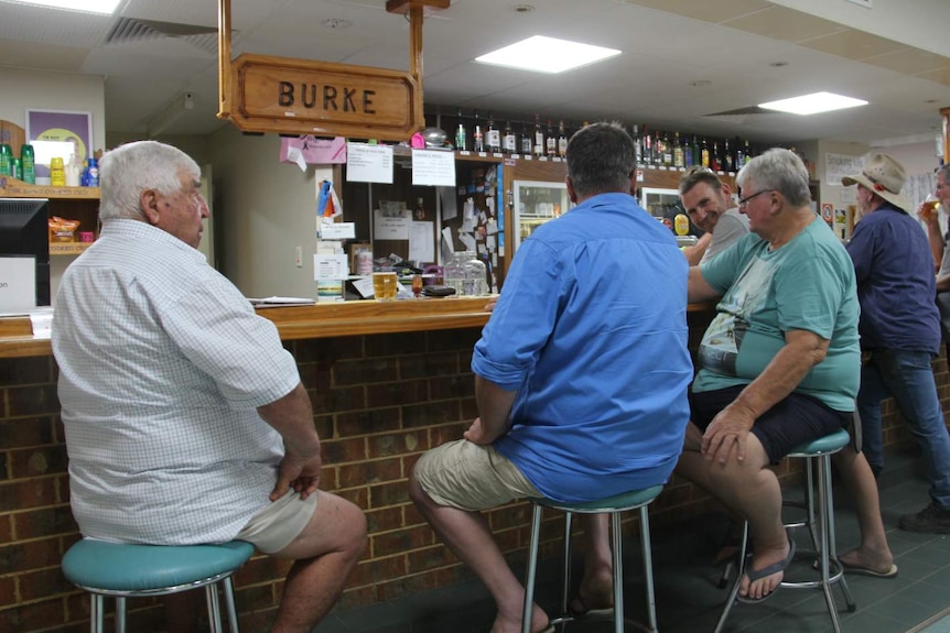 men in summer clothes sitting in country pub at bar