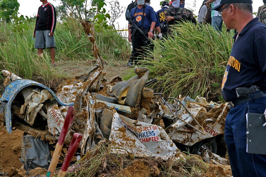 Philippine police stand guard during the recovery of bodies and mangled vehicles at Ampatuan massacre site