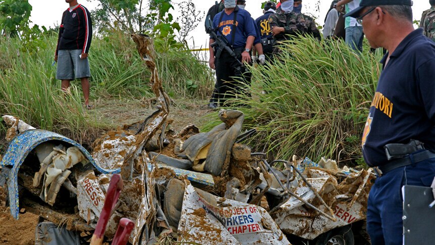 Philippine police stand guard during the recovery of bodies and mangled vehicles at Ampatuan massacre site