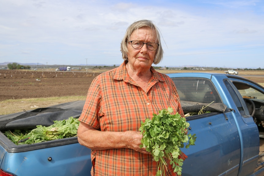 Mary Davies holds a bunch of coriander in front of her ute in the Lockyer Valley, January 2020.