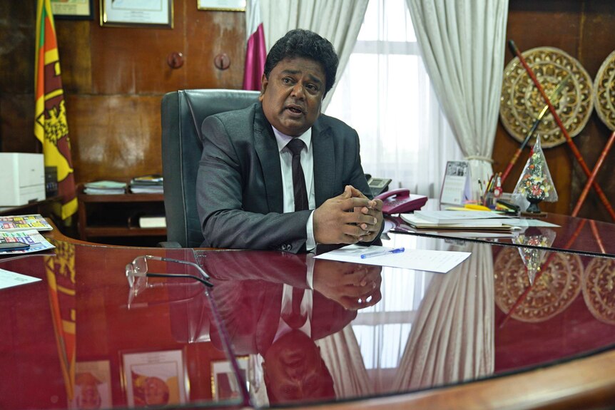 A Sri Lankan man sitting at a very big desk