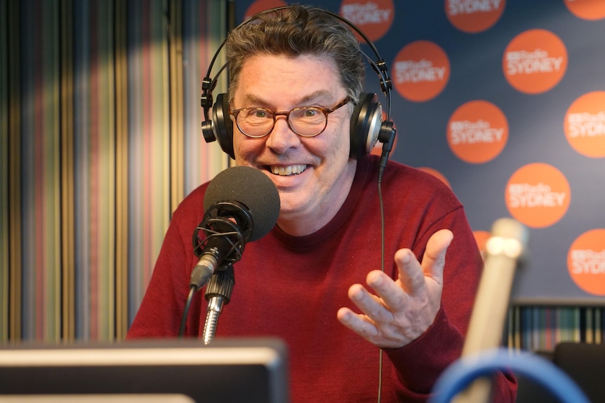Man wearing headphones in ABC radio studio sitting in front of microphone.