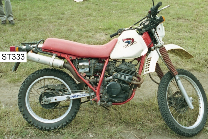 A 1987 red and white Honda trail motorcycle.