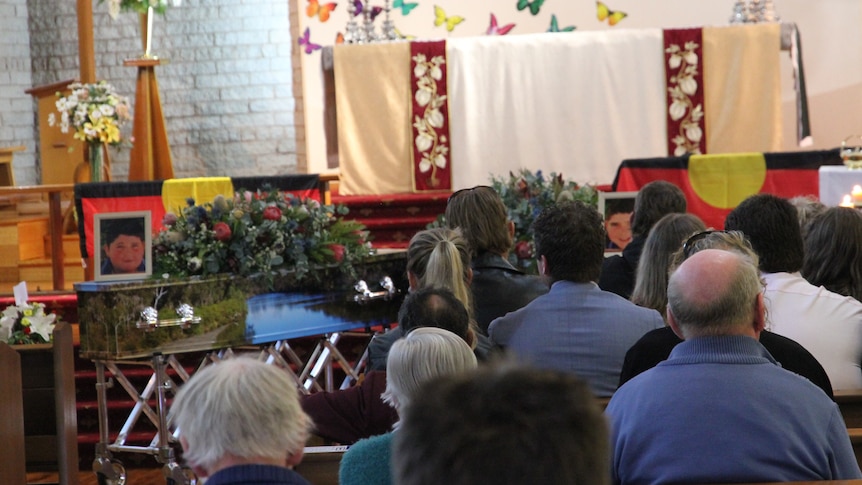 A crowd of people gather in a church for a funeral