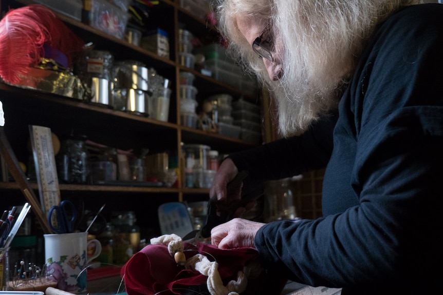 Sue Harris in her workshop, trimming the thread on a puppet.