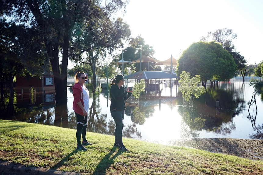 Two women standing alongside a flooded lake