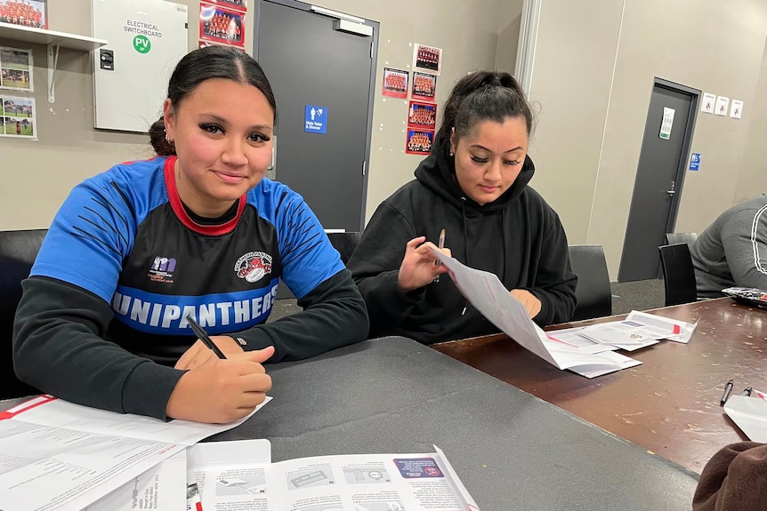 Pacific Island women sitting down filling out paper work