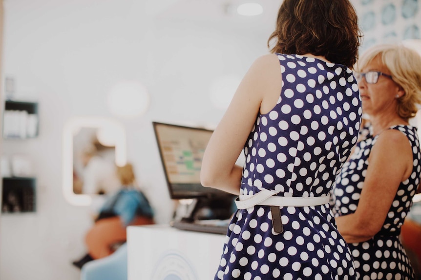 Two women wearing the same dress at a service counter