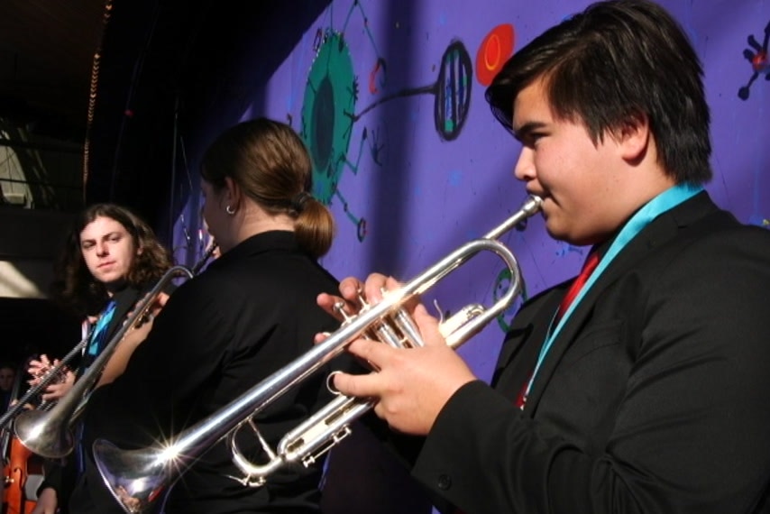 A young man plays a trumpet