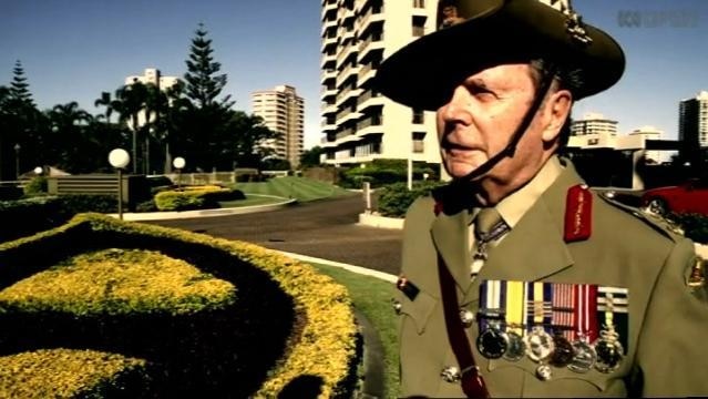 Man in war uniform and hat stands beside gardens