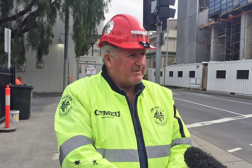 CFMEU organiser Kevin Harkins wears hivis and a hat in front of Royal Hobart Hospital