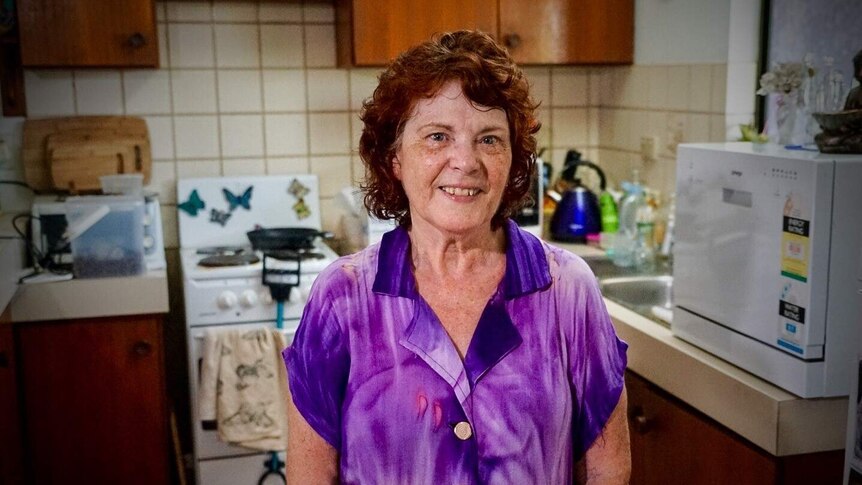 Red-haired lady standing in her kitchen.