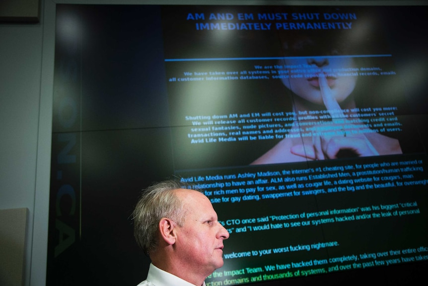 A police man stands in front of a picture of the Ashley Madison website.