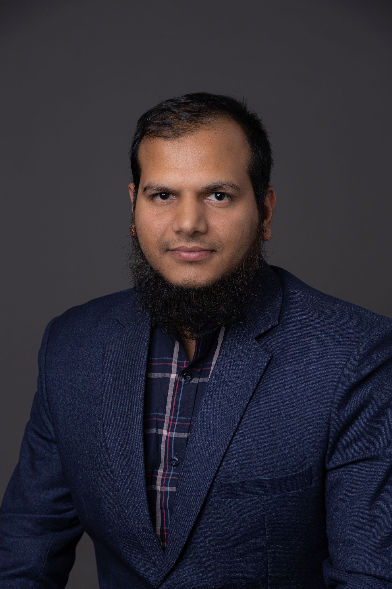 a man with black hair and beard looks to the camera