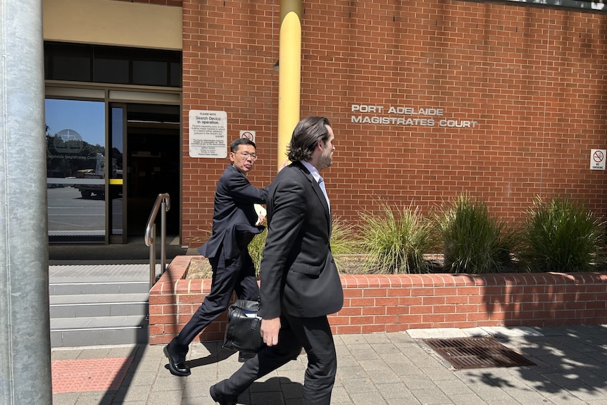Two men in black suits outside court.