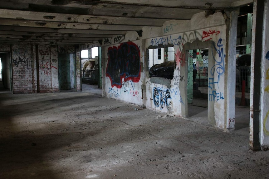 A dilapidated concrete building with broken glass and graffiti on the walls.