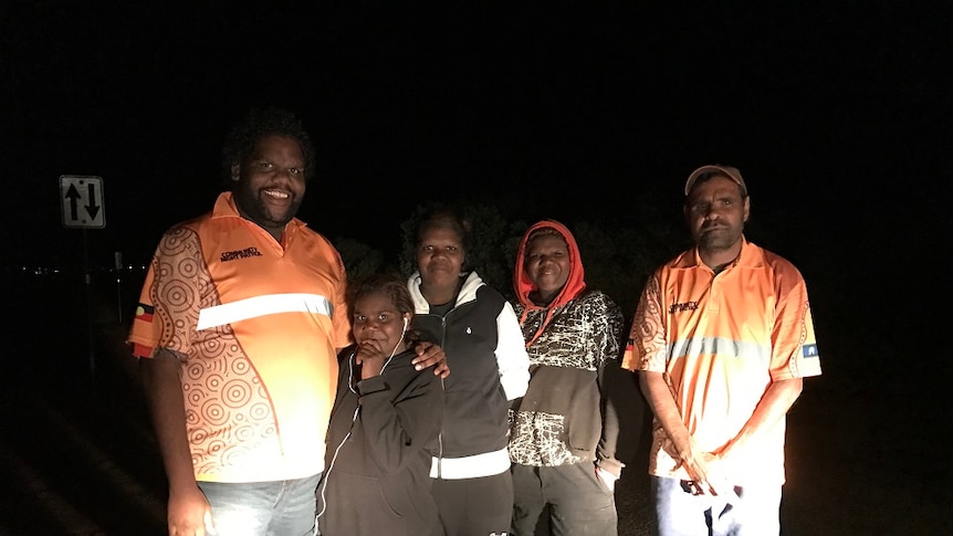 Kade Green and his colleague wear orange shirts, and stand with three young people