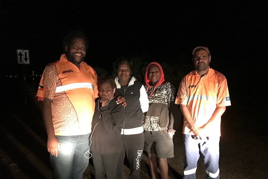 Kade Green and his colleague wear orange shirts, and stand with three young people