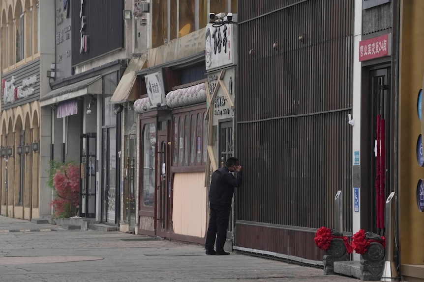 A security guard peers into a store past a series of neighboring Beijing restaurants