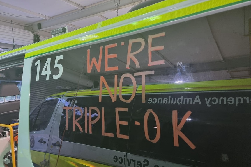 The side of an ambulance with "we're not triple-OK" written in chalk.