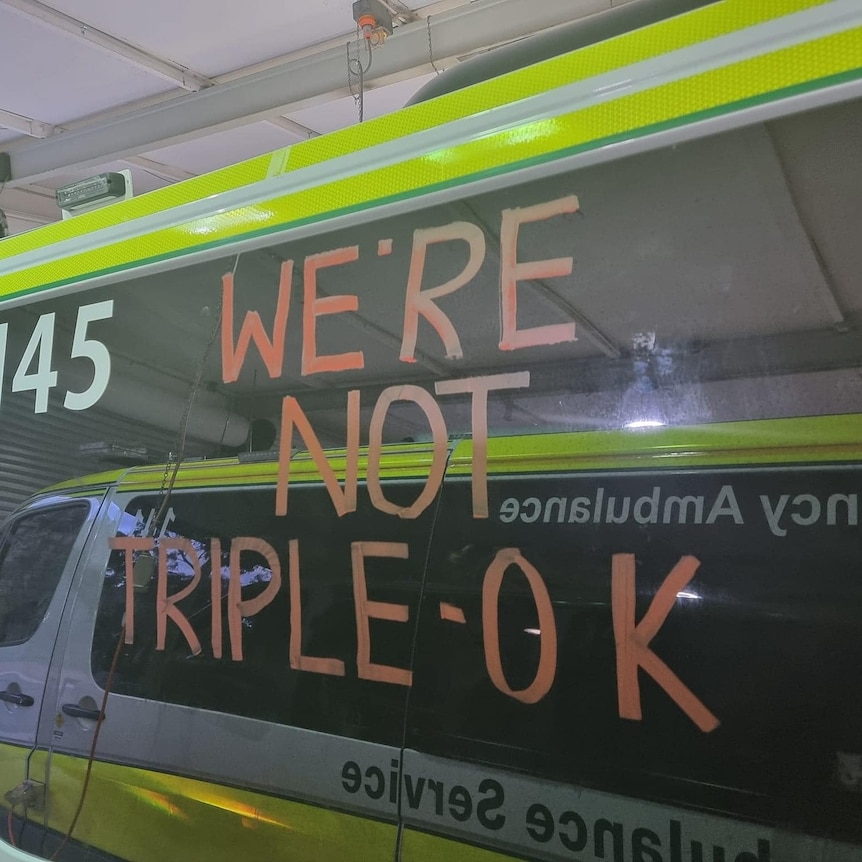 The side of an ambulance with "we're not triple-OK" written in chalk.