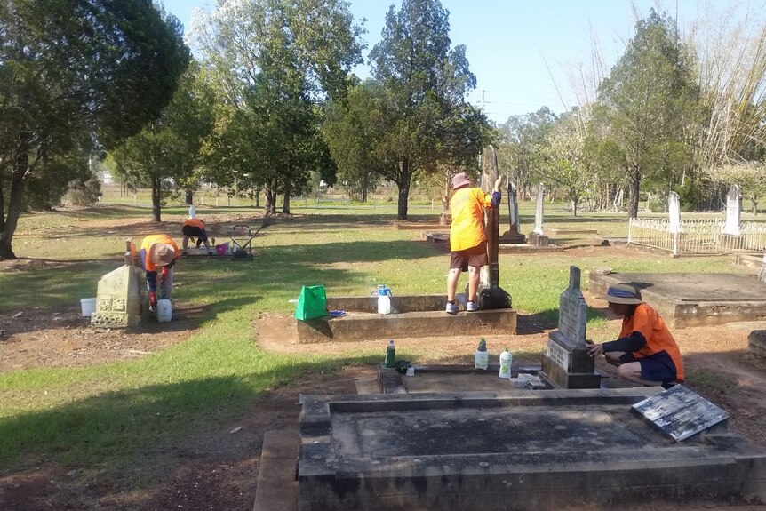A group of people scrubbing old tombstones.