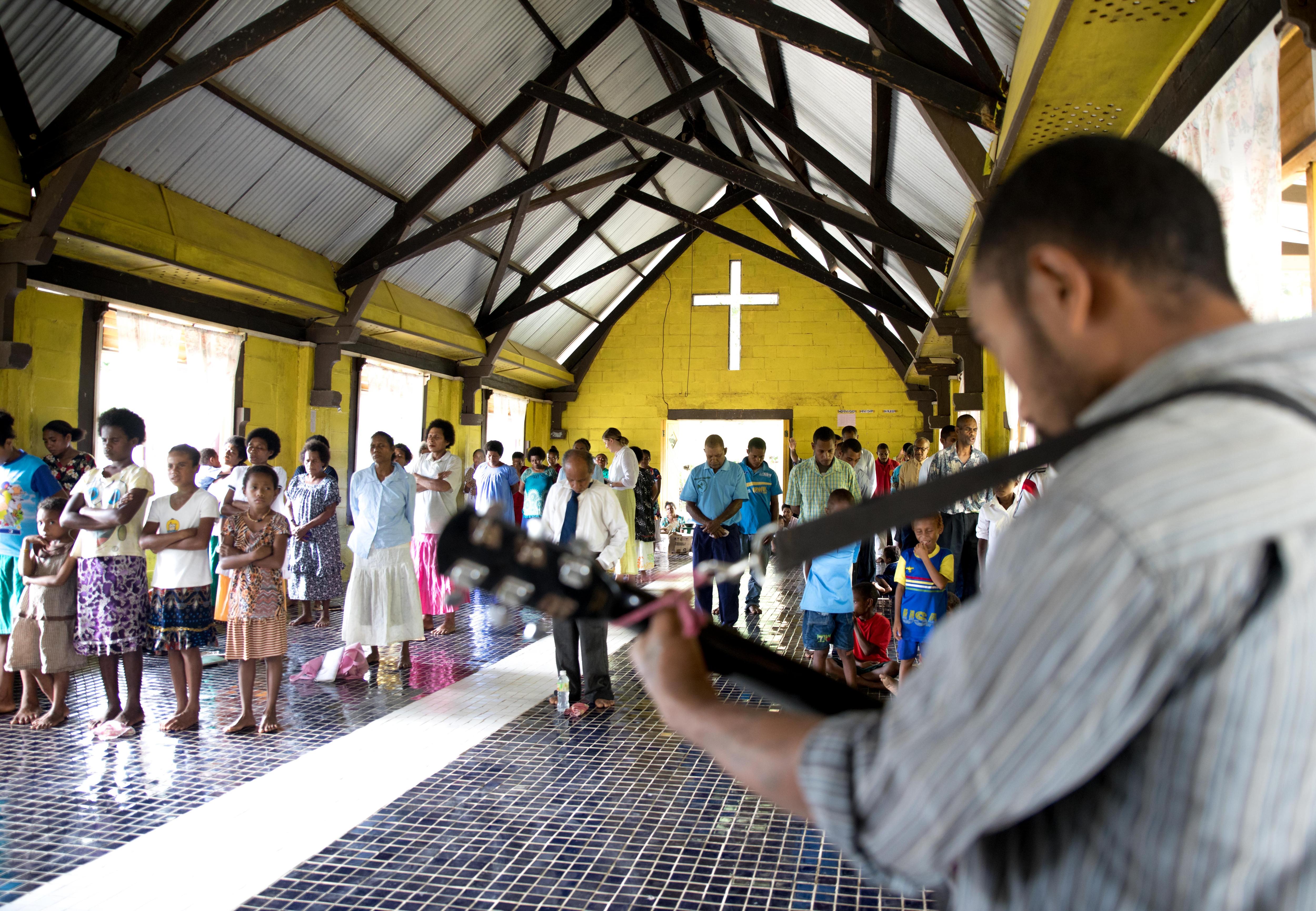 A church event in PNG. Worshipers are seen standing to watch a man playing his guitar.
