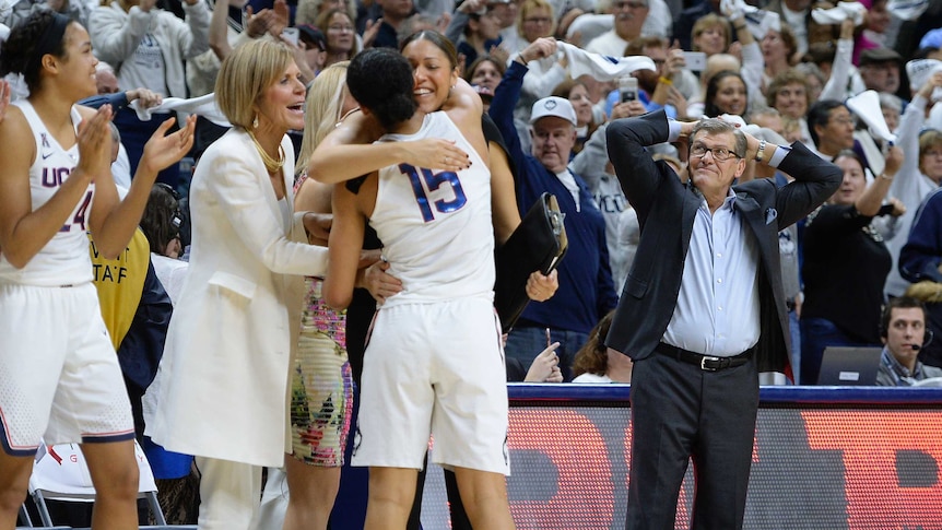 University of Connecticut coach Geno Auriemma (R) reacts as his team celebrates their milestone win.