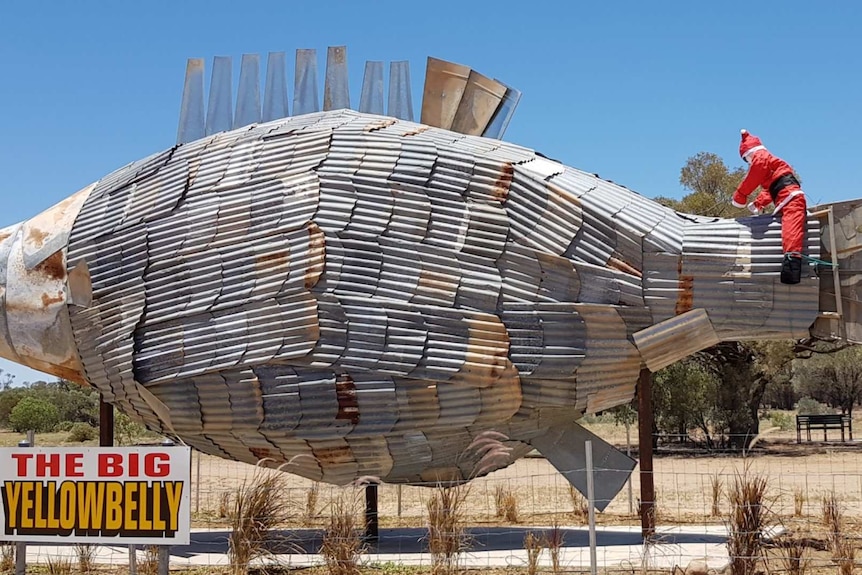 Stuffed Santa astride a large corrugated iron sculpture of a fish in Isisford, Queensland