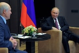 Russian President Vladimir Putin smiles as he listens to Belarusian President Alexander Lukashenko