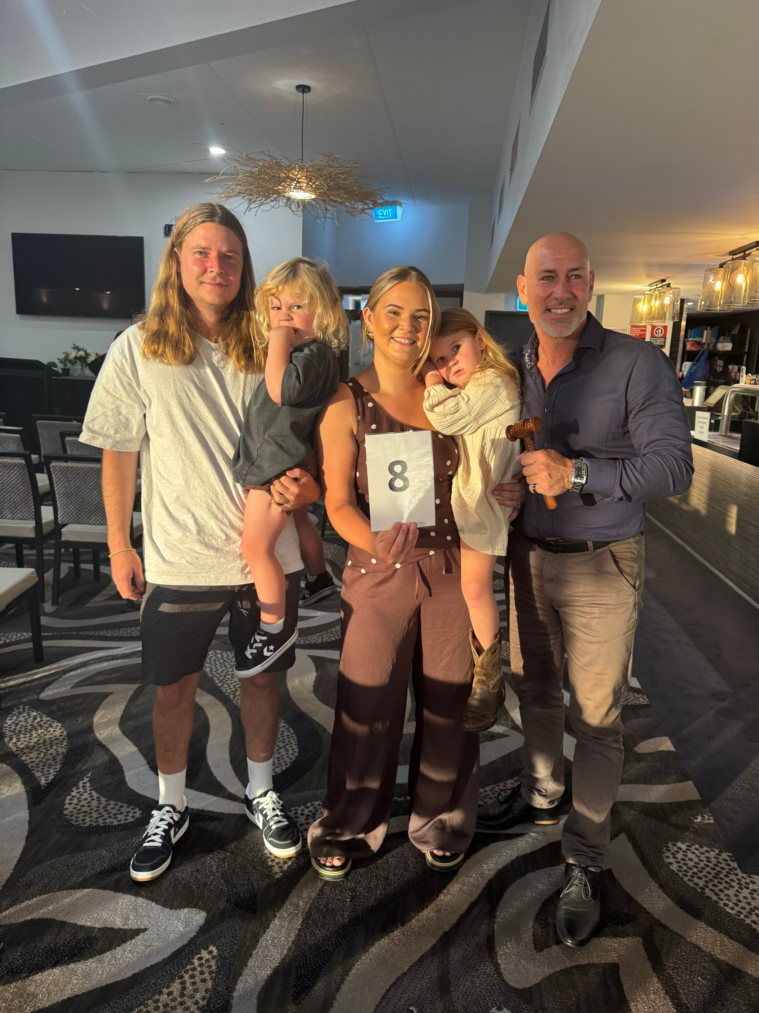 Uma jovem família ao lado de um leiloeiro após comprar sua primeira casa, eles sorriem