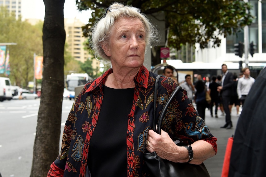 An elderly woman walks on a city street.