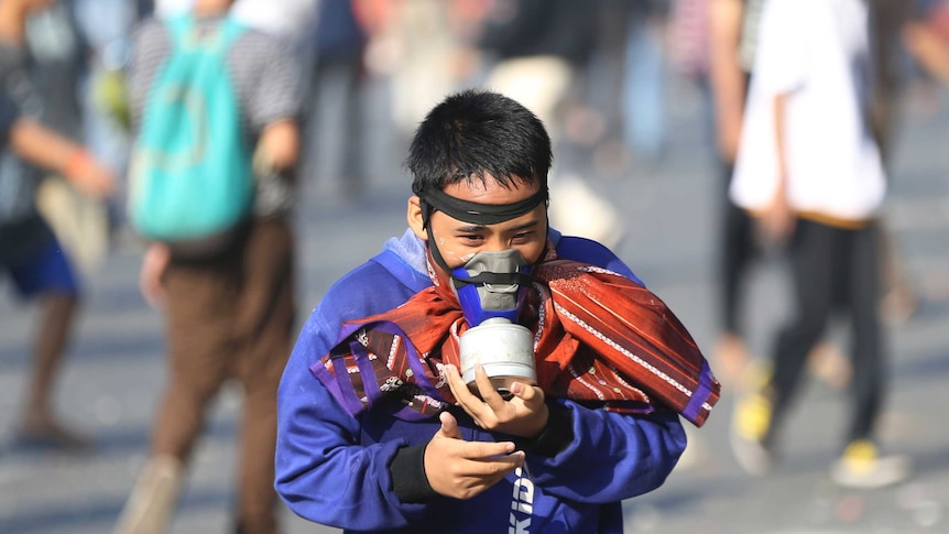 A supporter of Indonesian presidential candidate Prabowo Subianto runs while wearing a gas mask during a protest on the streets.