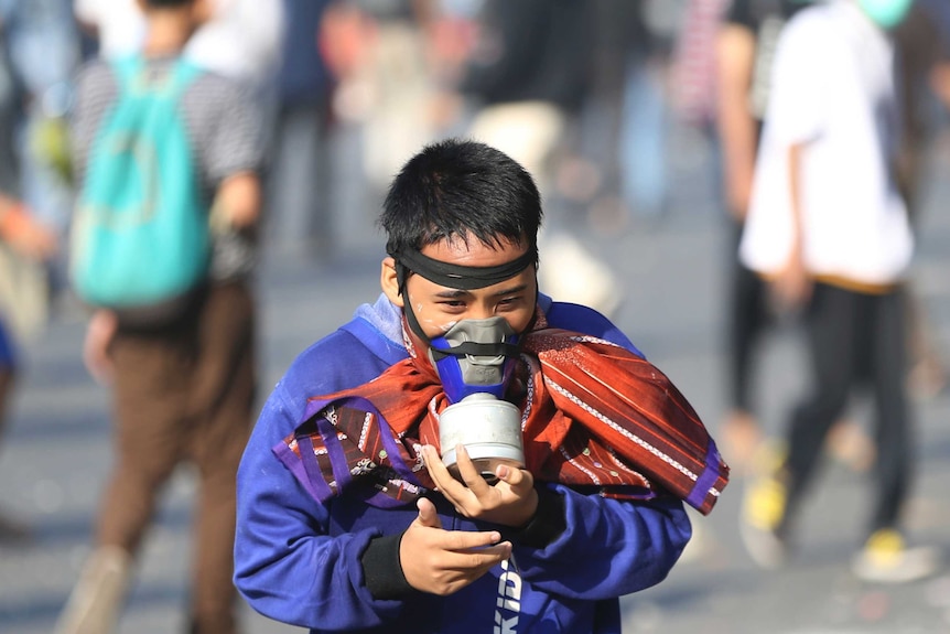 A supporter of Indonesian presidential candidate Prabowo Subianto runs while wearing a gas mask during a protest on the streets.