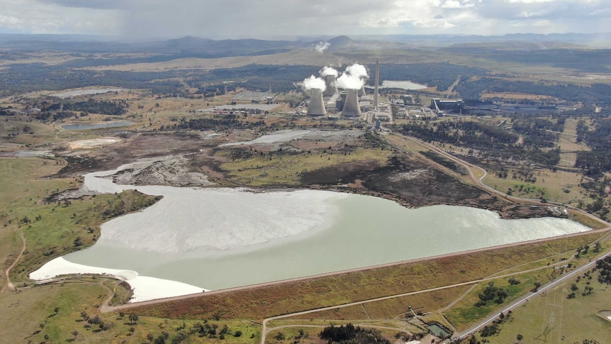 Aerial shot of large ash waste dam with a power station in the background
