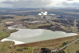 Aerial shot of large ash waste dam with a power station in the background