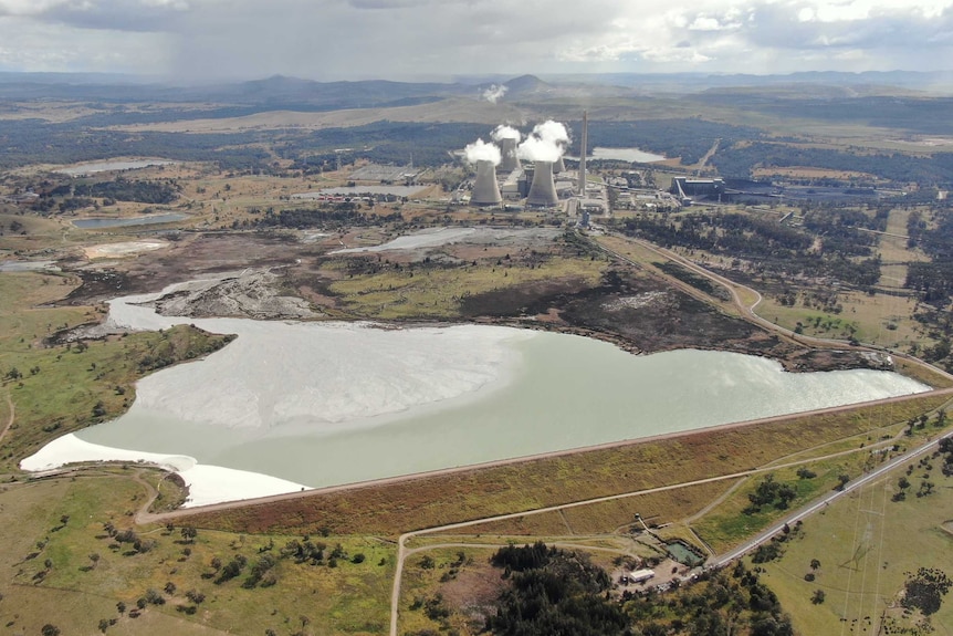 Aerial shot of large ash waste dam with a power station in the background