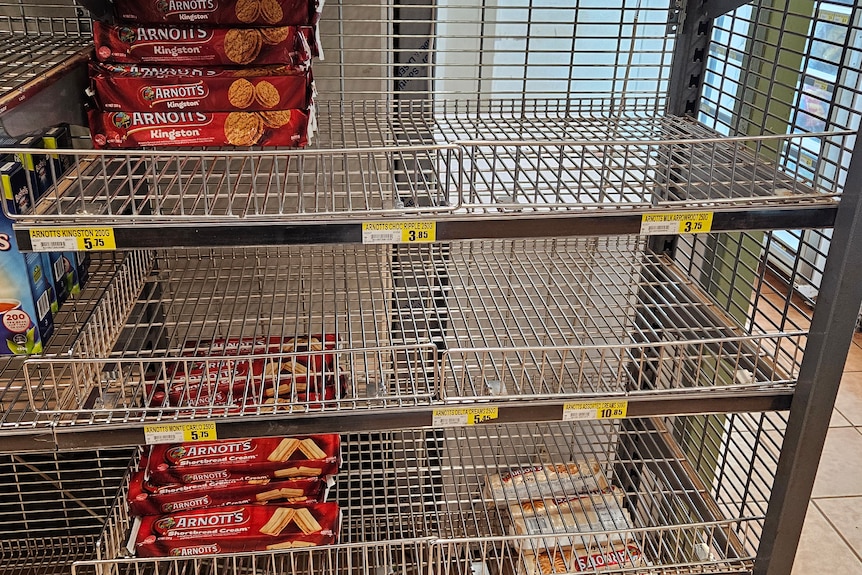a metal shelf with a few biscuit packets left