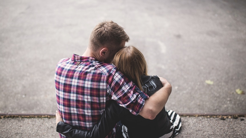 A man puts his arm around a teenager