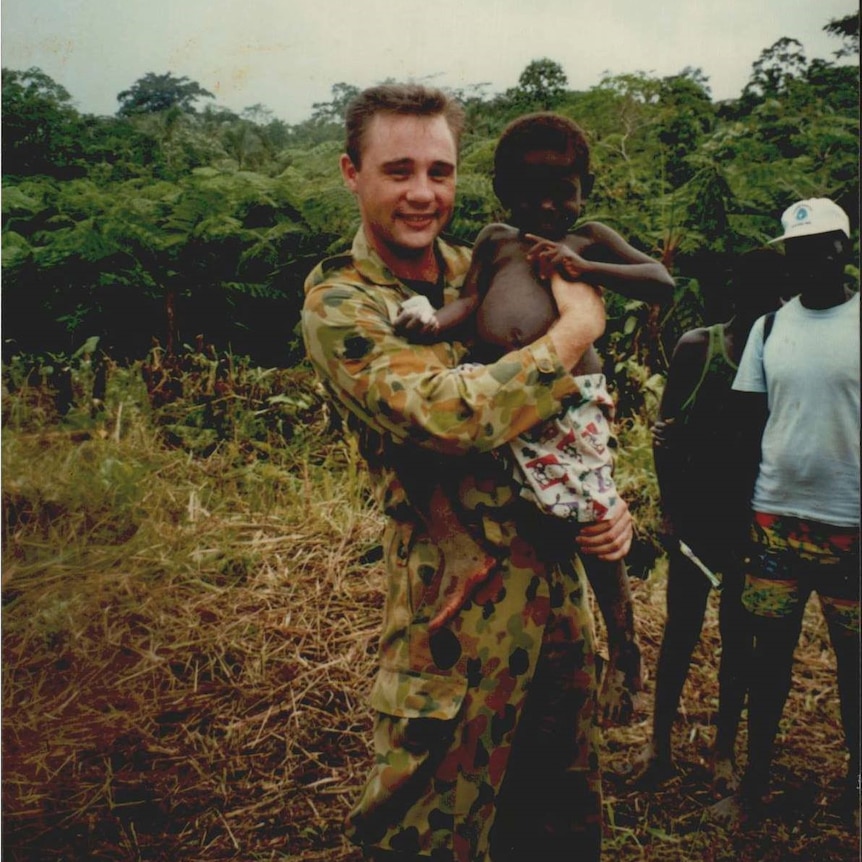 Australian soldier holds small child
