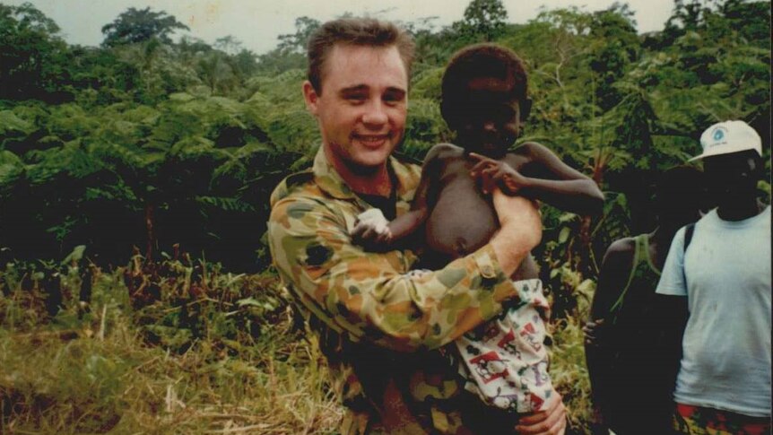 Australian soldier holds small child