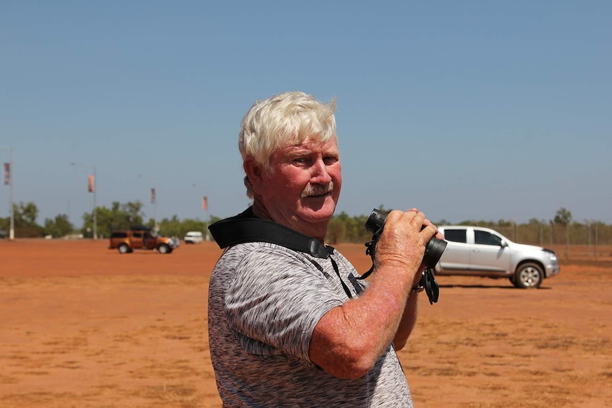 A photo of a plane spotter from NSW with his binoculars in his hand.