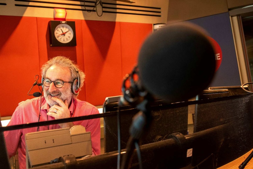 Jon Faine smiles while presenting his radio show in the studio