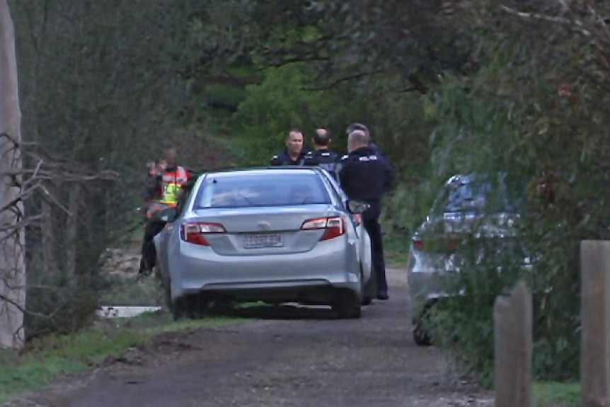Police in the driveway of the house at Hillier where three bodies were found